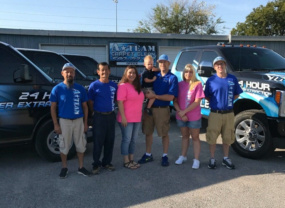A group of people standing in front of some cars.